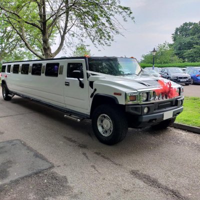 White stretch Hummer limousine dressed with wedding ribbons