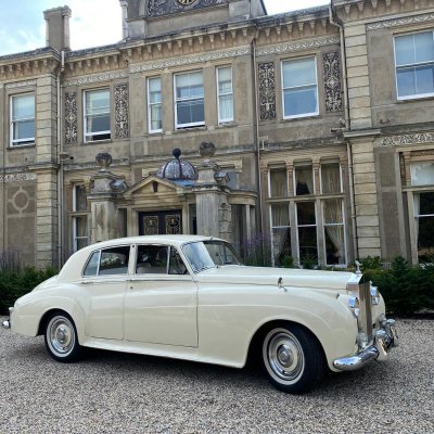 Ivory Rolls-Royce Silver Cloud wedding car outside a country mansion