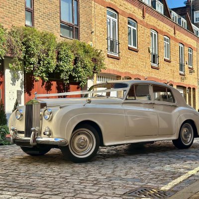 Ivory Rolls-Royce Silver Cloud with wedding ribbons on a cobbled London mews