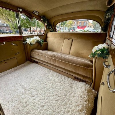 Gold interior of a classic wedding car dressed with white flowers